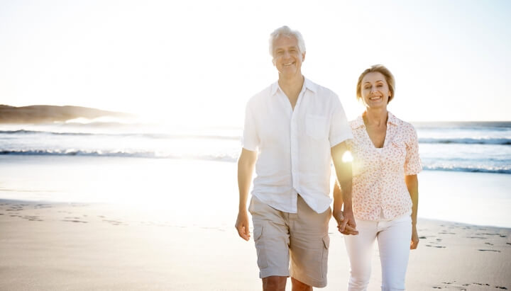 Happy elderly couple walking on the beach 