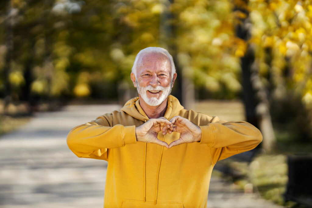 Portrait of smiling old sportsman gesturing heart shapePortrait of smiling old sportsman gesturing heart shape at camera for healthy sporty life. at camera for healthy sporty life.